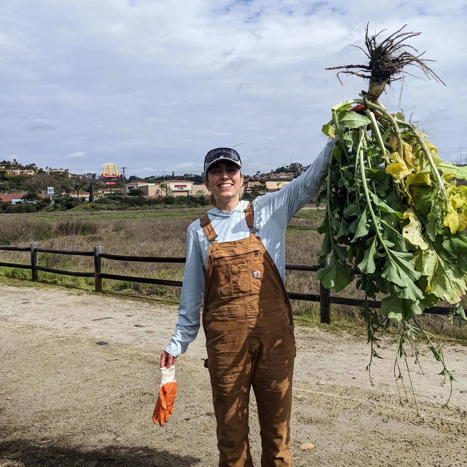 smiling woman holds invasive radish aloft