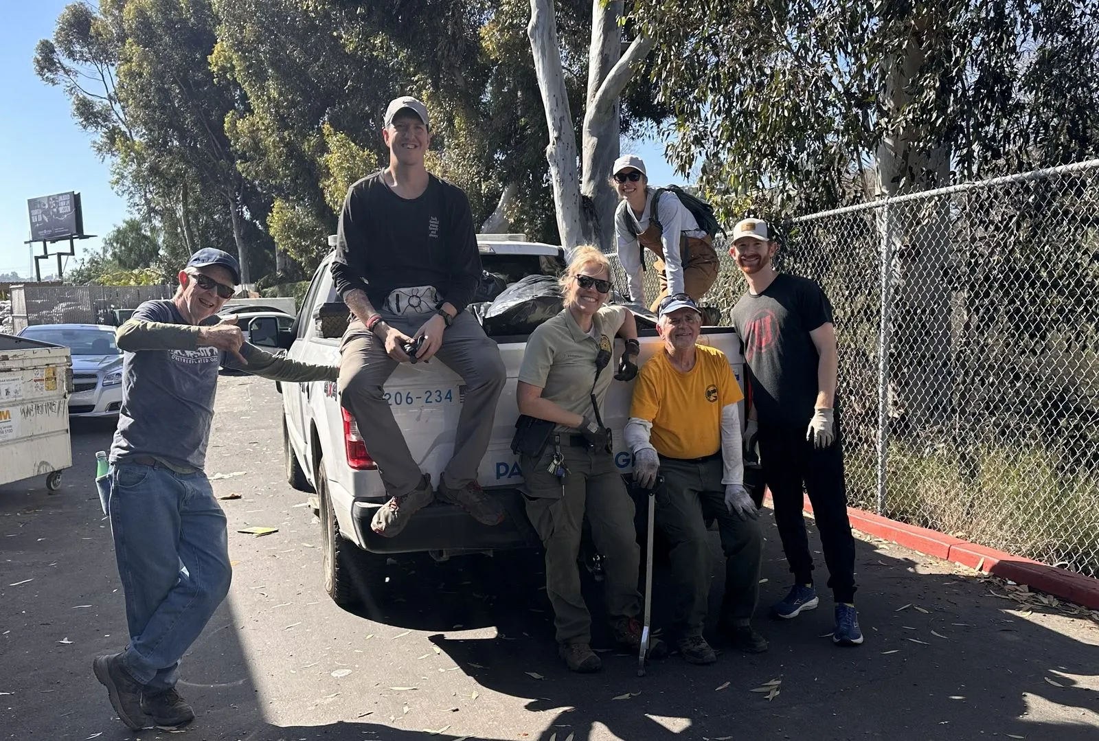 Group poses with truck full of trash bags