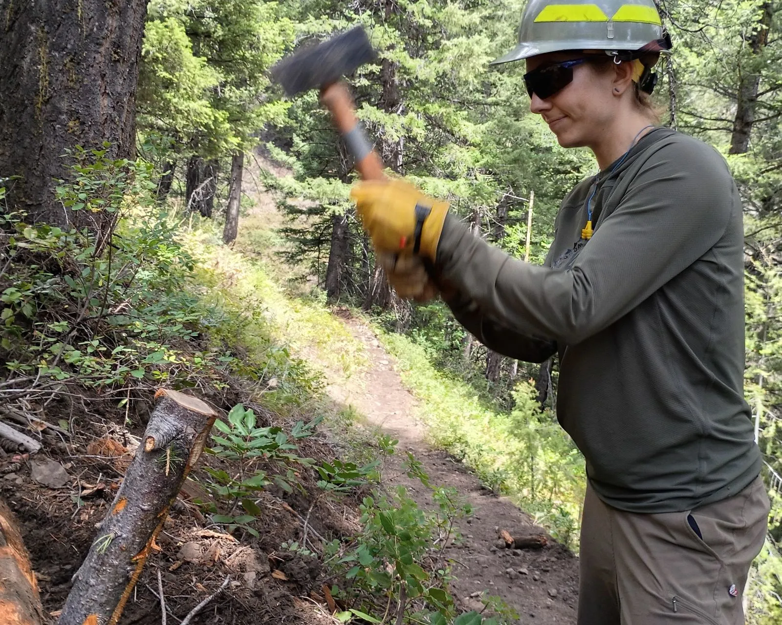 a woman hammers a wooden spike